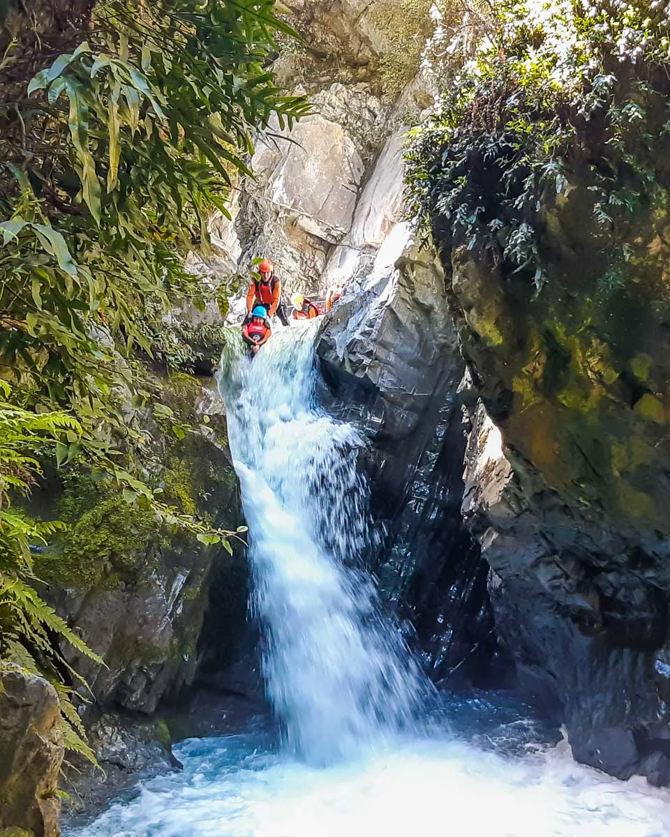 A person slides down a waterfall while canyoning in Queenstown