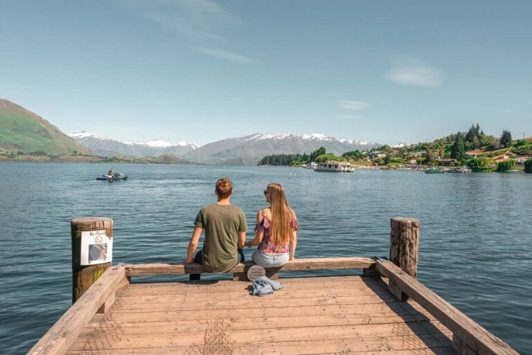 A couple sit on the Wanaka Jetty on a summers day