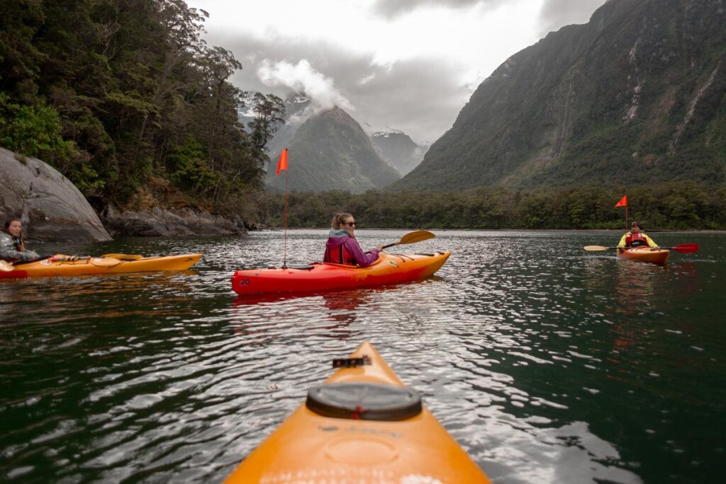 A lady Kayaks in Milford Sound while it's raining on a day trip from Queenstown