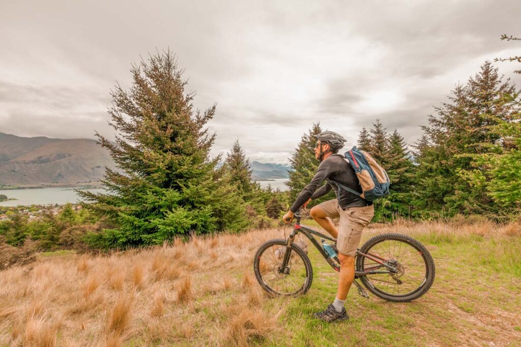 A man sits on his mountain bike overlooking Lake Wanaka
