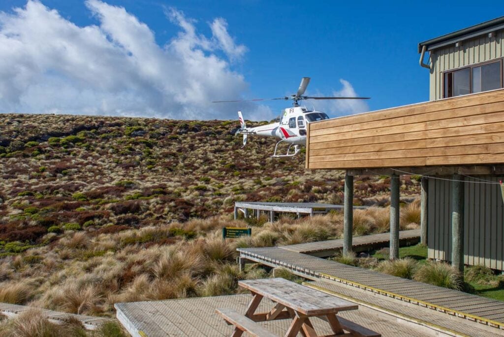 A helicopter lands at the Luxmore Hut