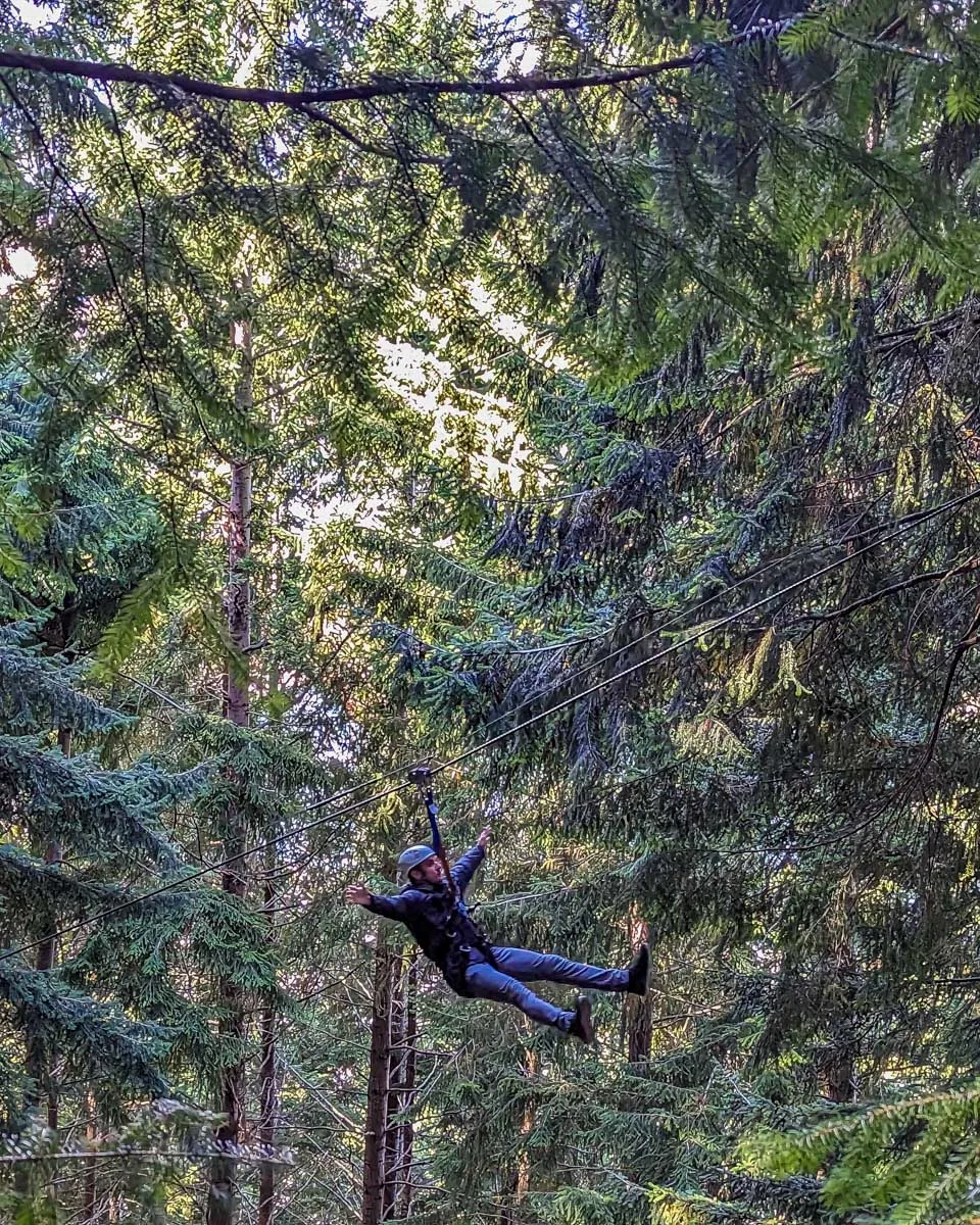 A man ziplining in Queenstown through the forest