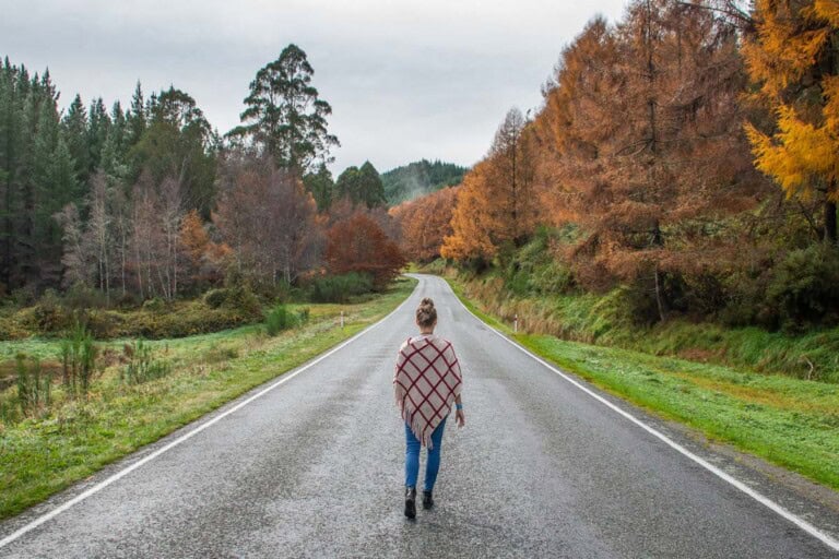 A lady stands in the middle of the road on New Zealand's west coast on the South Island near Franz Josef