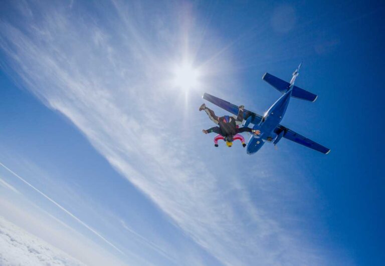 Two people on a tandem skydive exit a plane in NZ