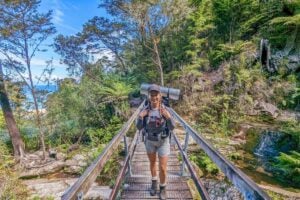 Bailey crosses a wooden briedge as she hikes the Abel tasman Coastal Track in NZ