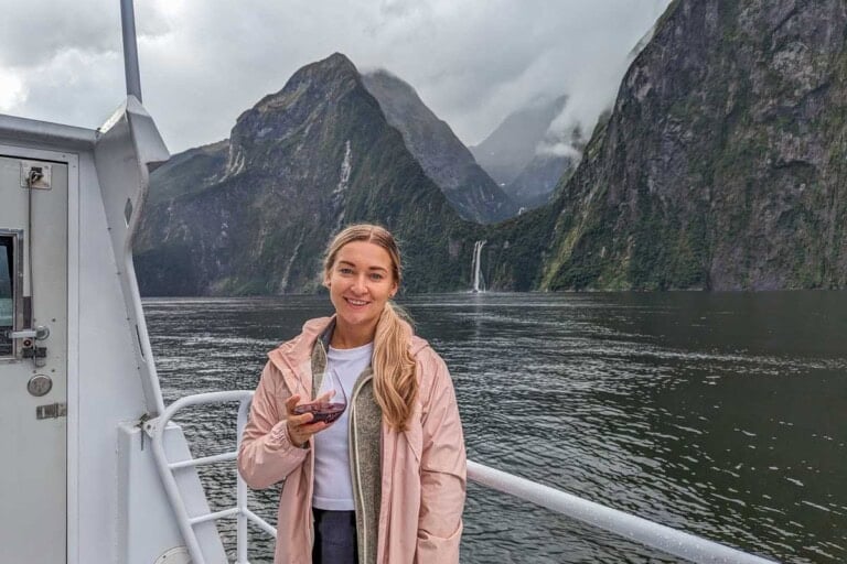 Bailey poses for a photo on the top deck on a Milford Sound cruise with a wine in her hand