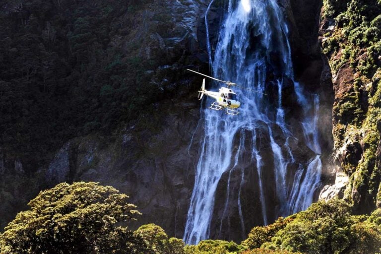 A helicopter flys through Milford Sound New Zealand on a tour