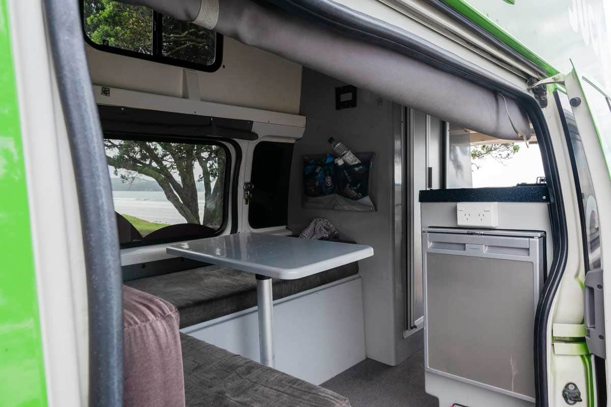 Looking insider of the jucy chaser campervan with seating and a table New Zealand