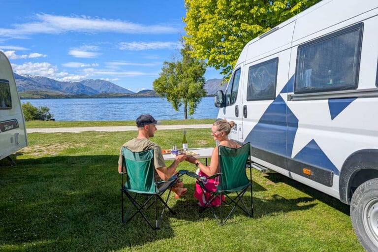 Daniel and Bailey sit by a lake with their Star RV campervan in New Zealand