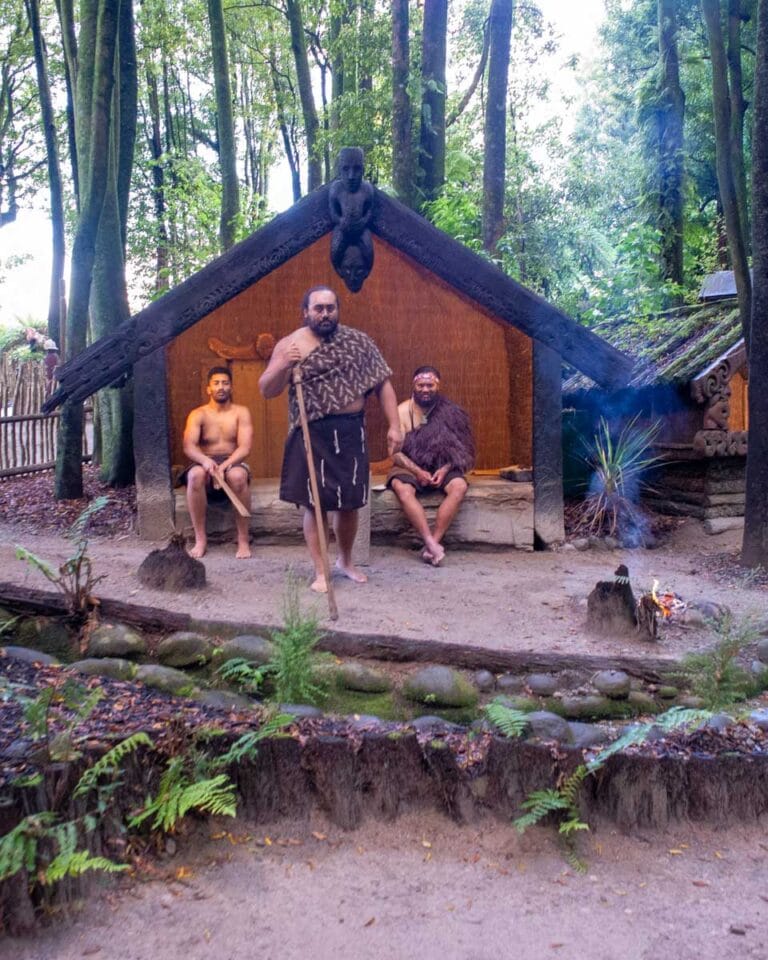 Three men outside of a hut at the Mitai Maori Village in Rotorua New Zealand