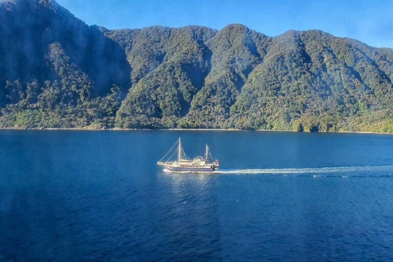 A ship cruises through the Milford Sound on a sunny day in New Zealand