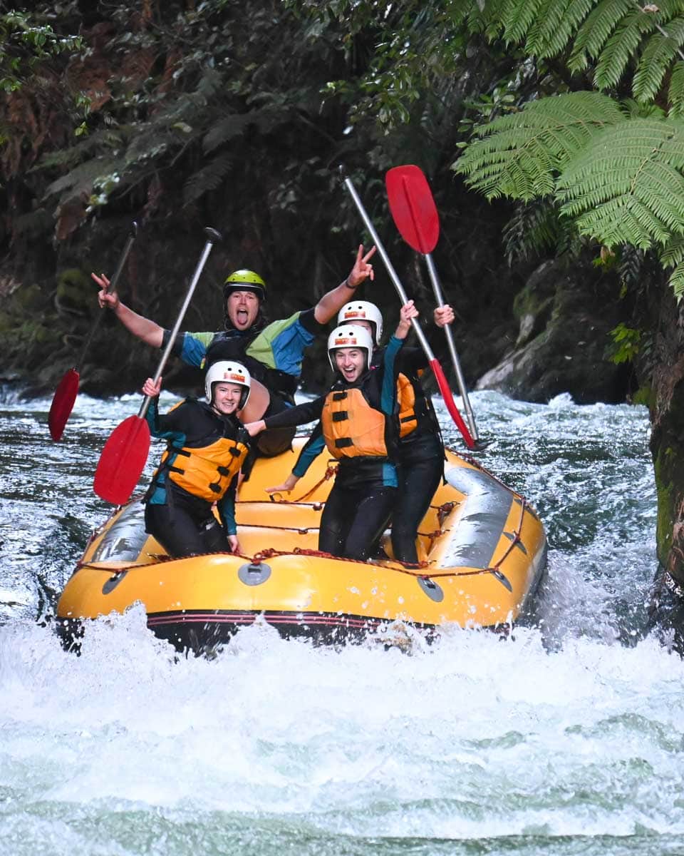A group of people cheer whitewater rafting down the Kaituna River in Rotorua