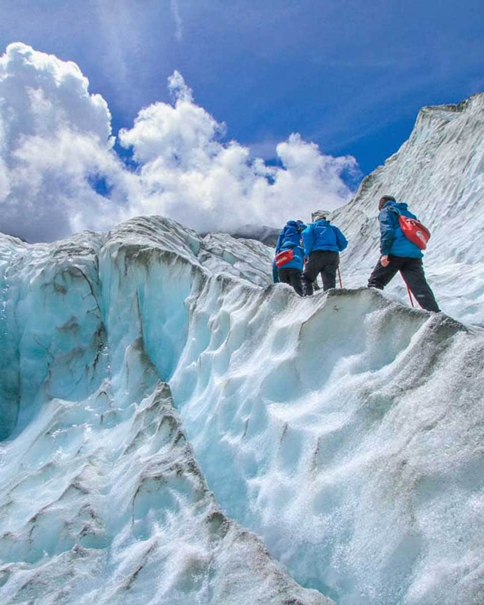 A group of people hike along a glacier in Franz Josef