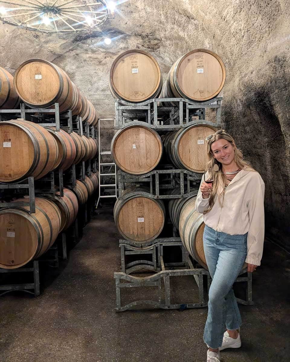 Bailey drinks wine in the Gibbston Valley wine cellar on a tour from Queenstown