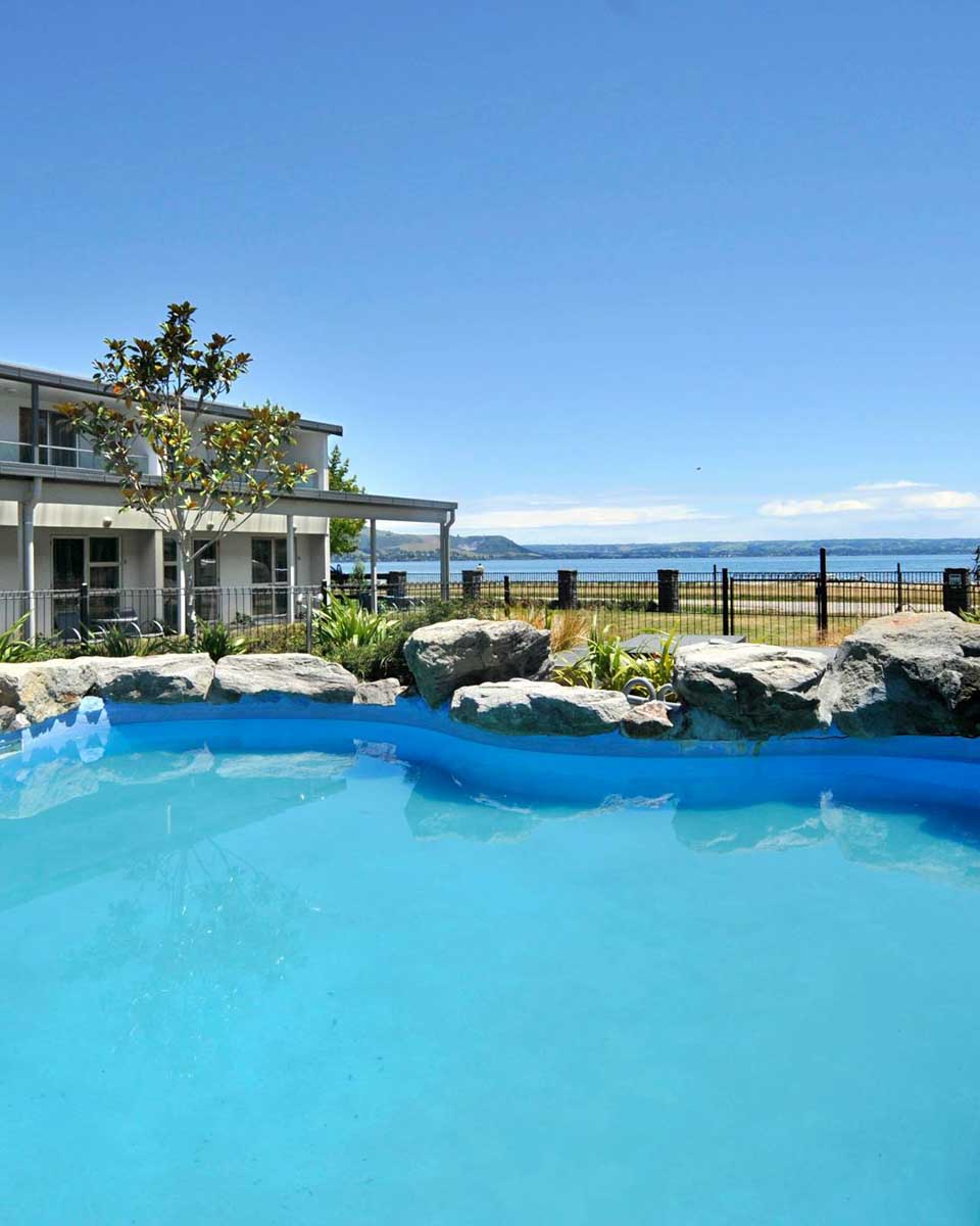 Outdoor pool with lake view at WaiOra Lakeside Spa Resort